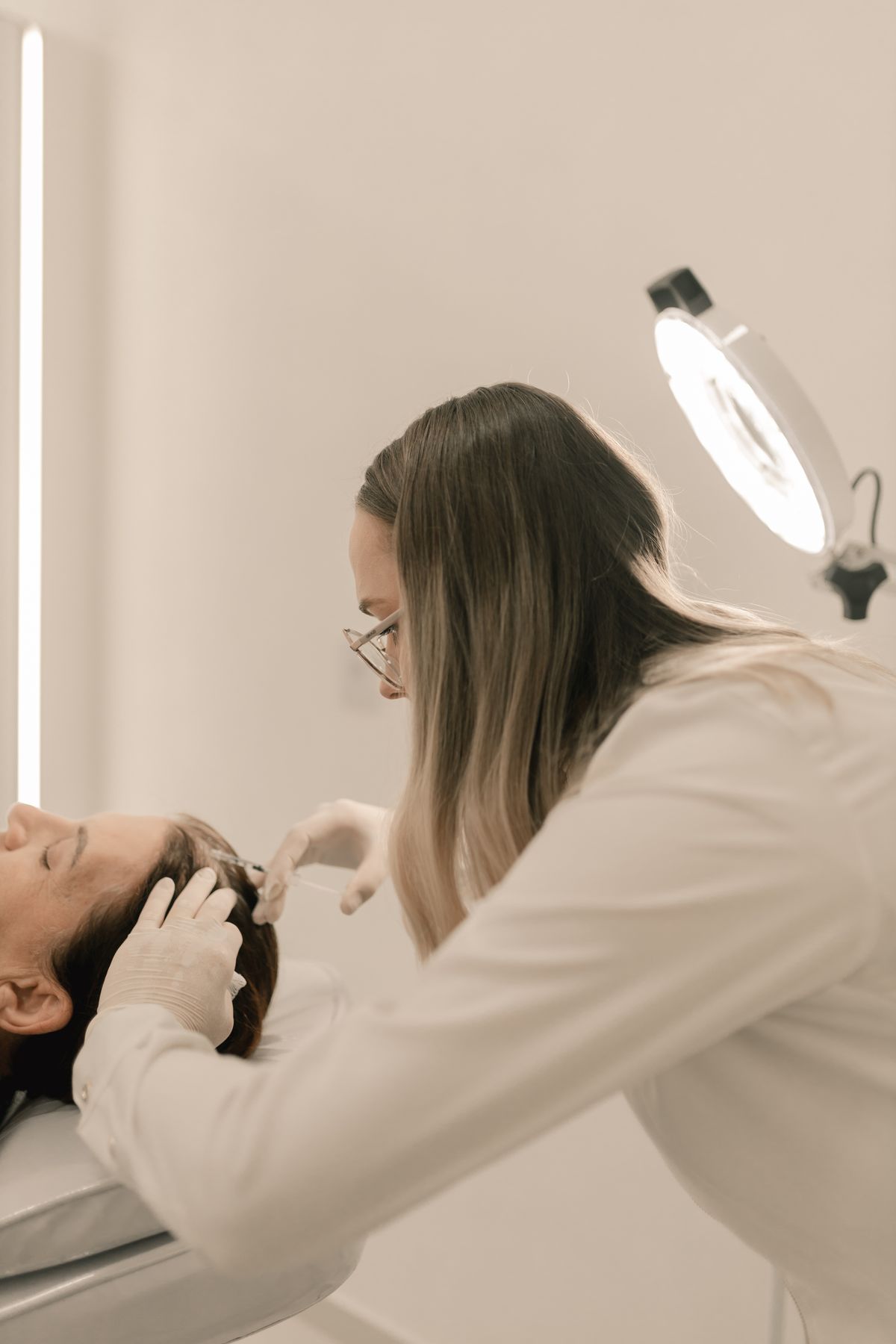 Especialista aplicando mesoterapia capilar en el cuero cabelludo de una paciente